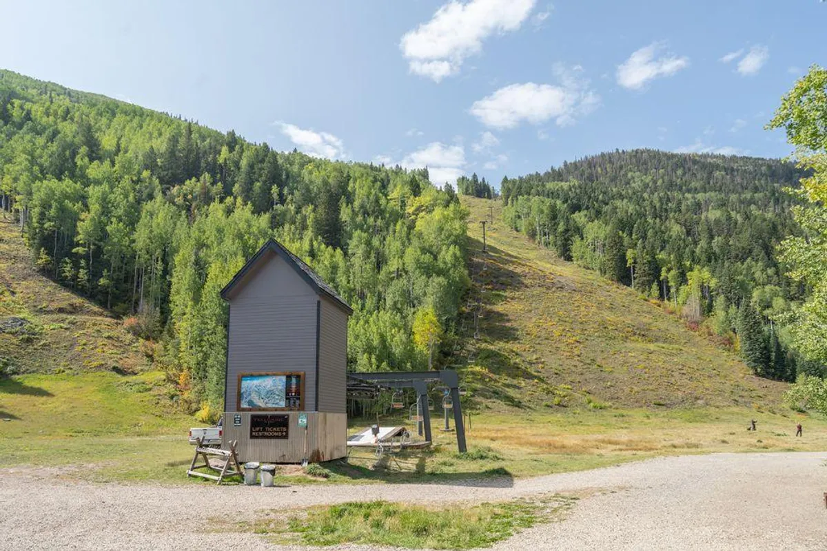This image captures the base of a ski lift nestled within a dramatic mountain landscape. An information board and a seating area are visible, surrounded by snowy terrain and crisp mountain air, evoking the heart of Telluride’s ski culture and the ski-in/ski-out experience.